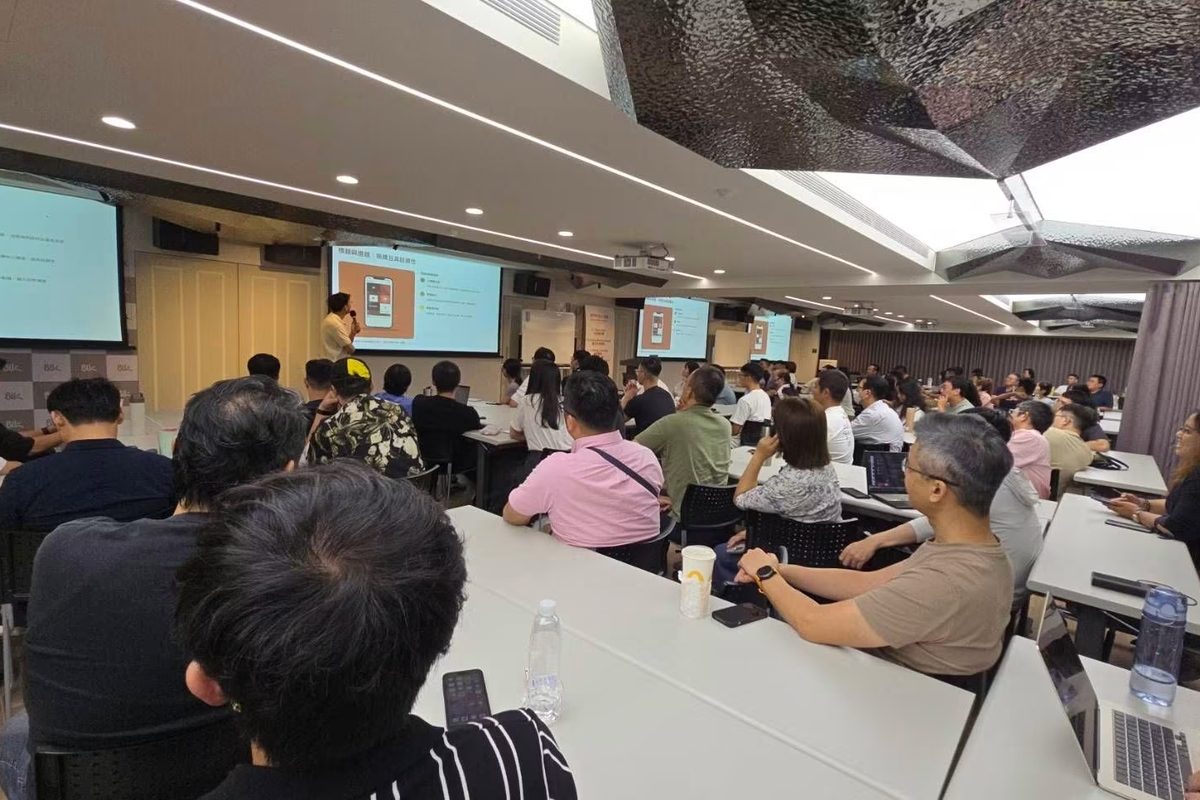課堂現場：學員坐滿長桌，看著前方投影幕上的簡報，講師站在螢幕旁