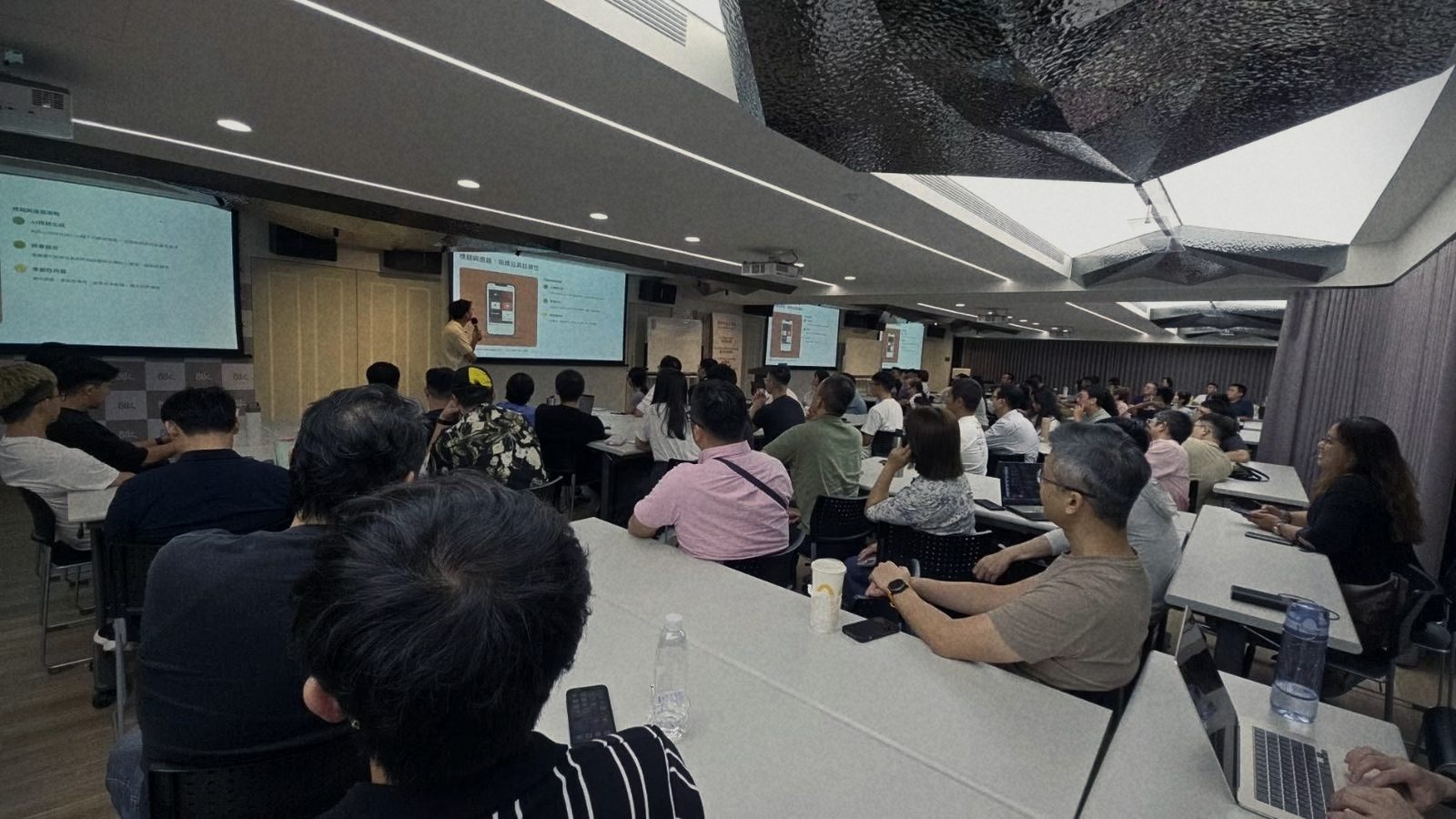 實體課現場，學員坐滿長桌看向前方投影幕
